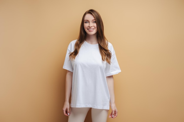 mujer sonriente con cabello largo con camiseta blanca mirando a la cámara aislada en el fondo Mockup