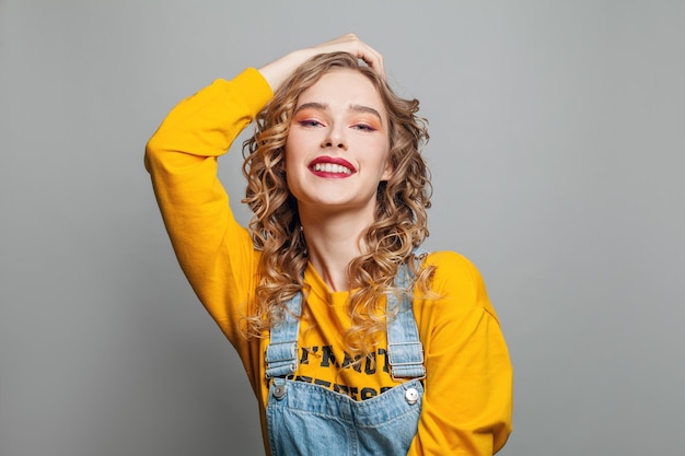 Mujer sonriente con cabello rizado rubio sobre un fondo blanco