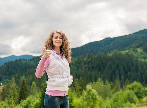 Mujer sonriente en un campo con el pulgar arriba