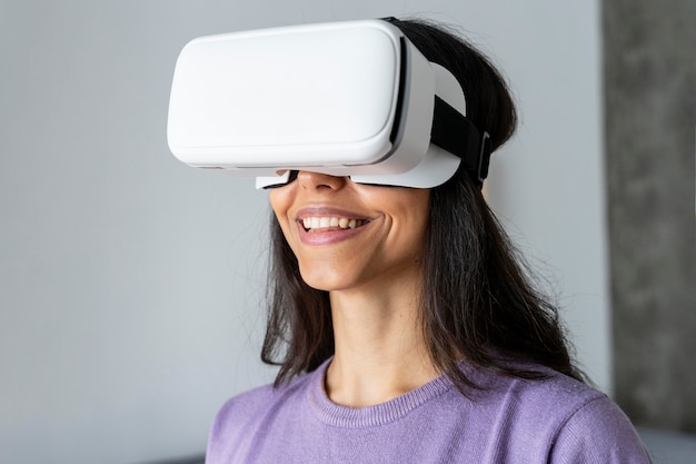 Mujer sonriente con casco de realidad virtual en casa
