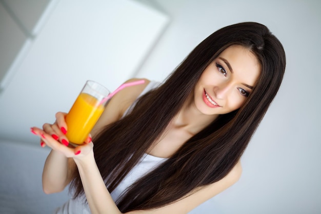 Foto mujer sonriente casual sosteniendo un vaso de jugo de naranja