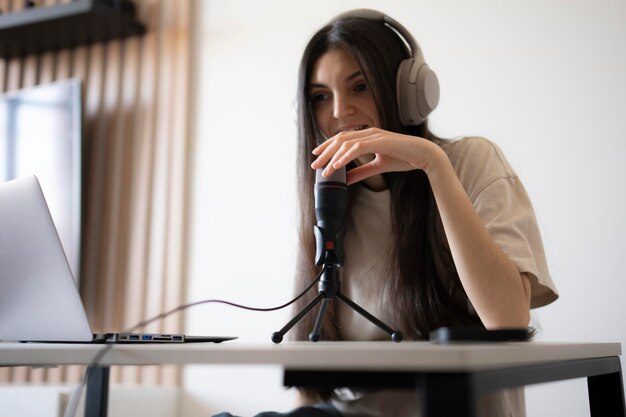 Mujer sonriente en una charla en línea con micrófono y auriculares en casa