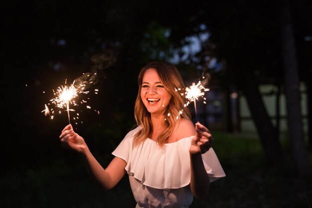 Mujer sonriente con chispas en la noche