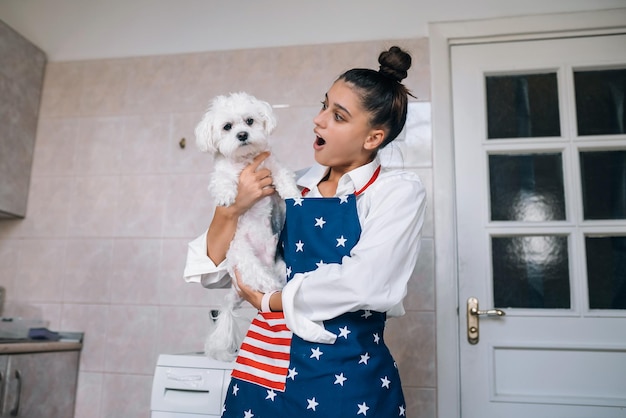 Mujer sonriente en la cocina con lindo perro maltés blanco