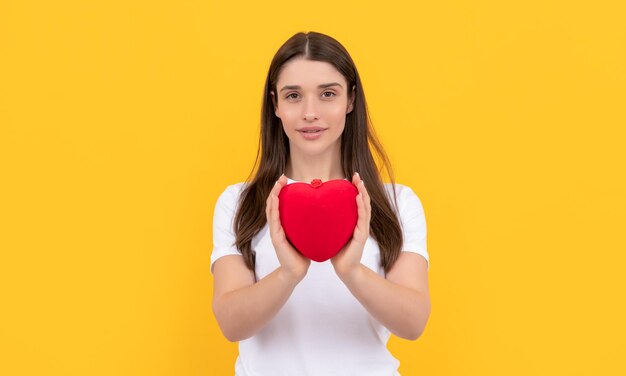 Mujer sonriente comparte corazón de amor en camisa blanca sobre fondo amarillo 14 de febrero