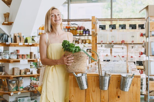 Mujer sonriente comprando alimentos orgánicos y productos ecológicos en una tienda sostenible libre de plástico