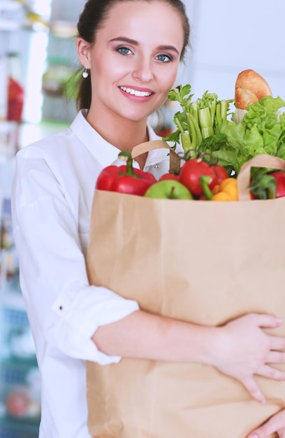 Mujer sonriente comprando en línea usando tableta y tarjeta de crédito en la cocina