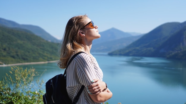 Mujer sonriente contra el lago y el paisaje de montaña. Paisaje del lago del embalse de Zhinvali con montañas. La principal cresta del Cáucaso.