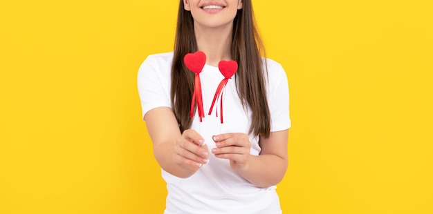 Mujer sonriente con corazón de amor en camisa blanca sobre fondo amarillo día de san valentín