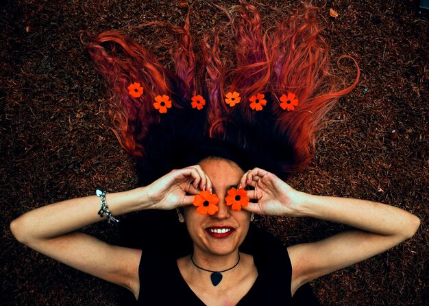 Foto mujer sonriente cubriendo los ojos con flores