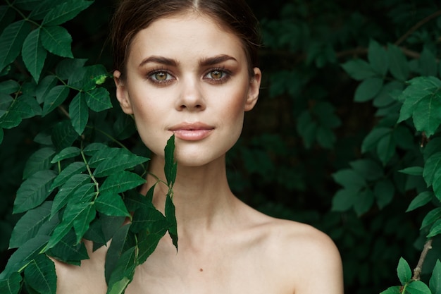 Mujer sonriente cuidado de la piel hombros desnudos hojas verdes modelo de naturaleza