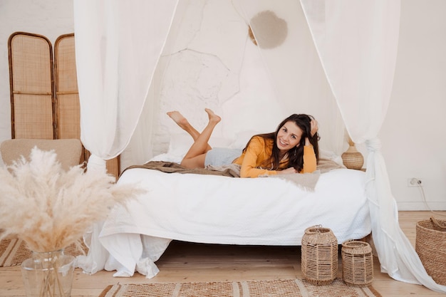 mujer sonriente despierta después de un sueño saludable acostada en una cama cómoda y acogedora disfruta de buenos días