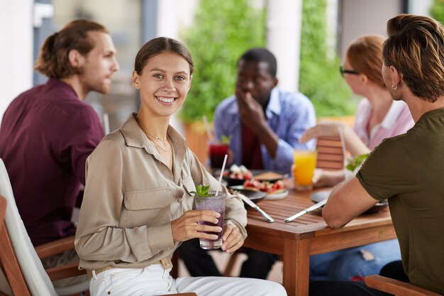 Mujer sonriente disfrutando de un almuerzo con amigos en el café