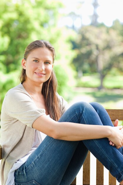 Mujer sonriente disfrutando del sol en un banco del parque