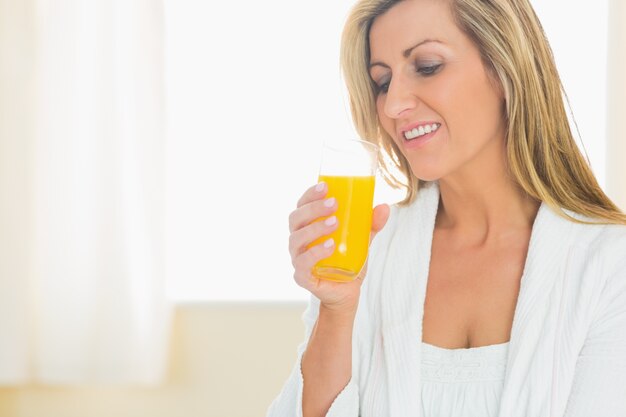 Mujer sonriente disfrutando de un vaso de jugo de naranja