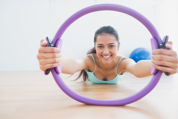 Mujer sonriente con ejercicio anillo en gimnasio