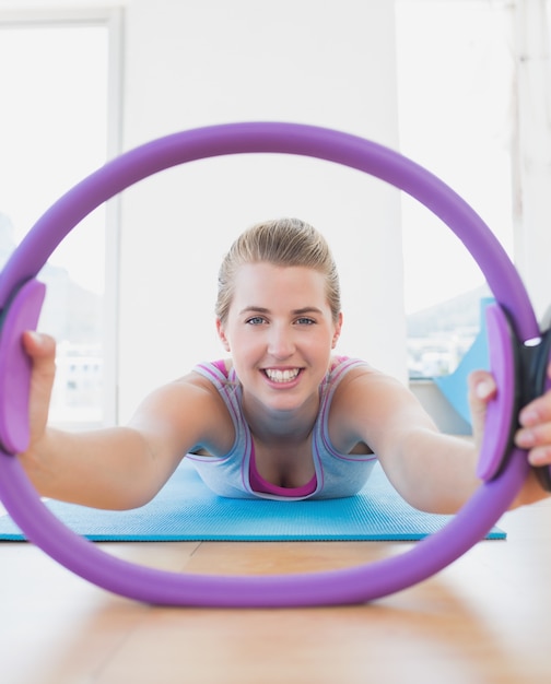 Mujer sonriente con ejercicio anillo en gimnasio