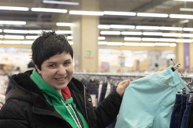 Una mujer sonriente elige ropa informal en una tienda Comercio minorista