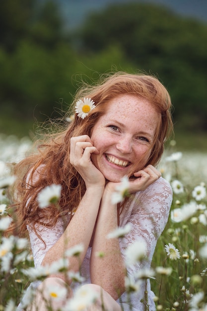 La mujer sonriente encantadora joven se pregunta en la flor, rasgando los pétalos, primer.