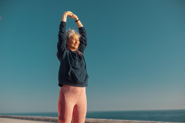 Mujer sonriente entrenando activamente sea el paseo marítimo