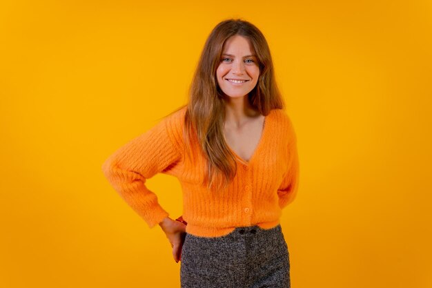 Mujer sonriente escondiendo un regalo sorpresa en su espalda con un fondo amarillo