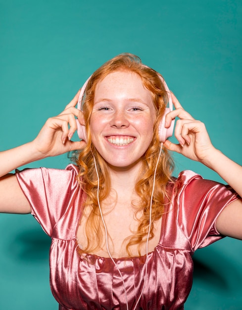 Foto mujer sonriente escuchando música con auriculares