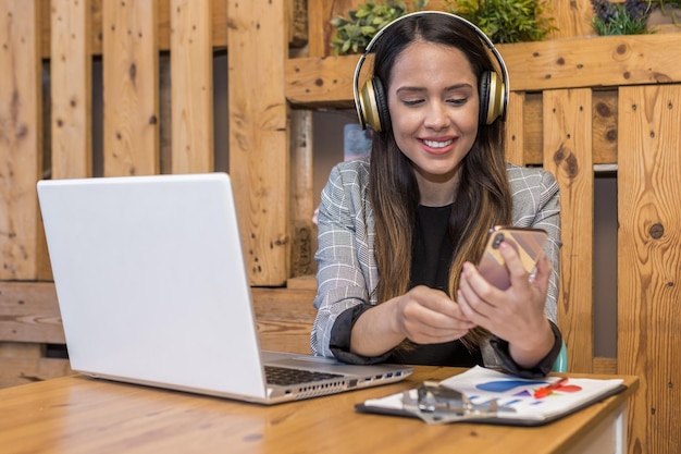 Mujer sonriente escuchando música mientras trabaja en línea