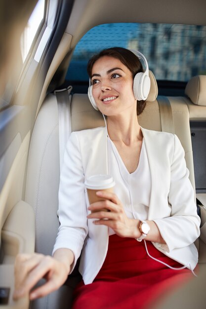 Mujer sonriente escuchando música en taxi