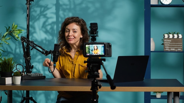 Mujer sonriente en el estudio usando una cámara profesional para grabar video