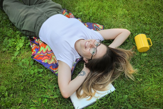 Una mujer sonriente feliz descansa en un parque con una vista superior del césped