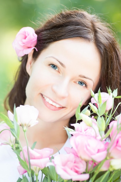 Mujer sonriente feliz con hermosas flores contra el fondo verde primavera