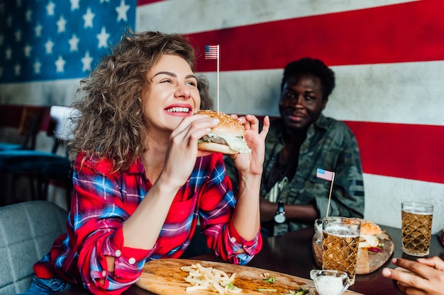 mujer sonriente feliz que tiene un descanso en el bar con el hombre en el café, hablando, riendo comer comida rápida.