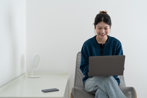 Mujer sonriente feliz sentada en el sofá y usando una computadora portátil en la sala de estar en casa viendo videos divertidos aprendiendo idiomas videollamadas madre trabajando en línea