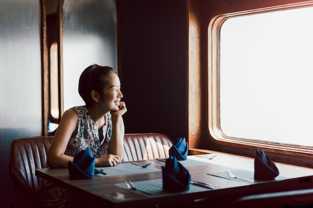 Mujer sonriente feliz sentada sola en el restaurante mirando hacia otro lado