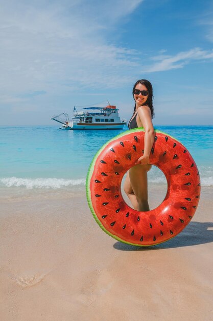 Mujer sonriente feliz sosteniendo un anillo inflable pequeño crucero en el fondo