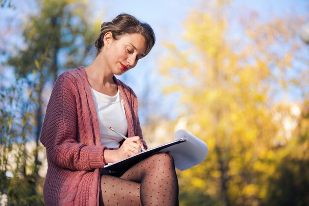 Mujer sonriente feliz trabajando con papeles y escribiendo cartas