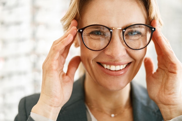 Mujer sonriente con gafas frente al escaparate en una tienda de óptica