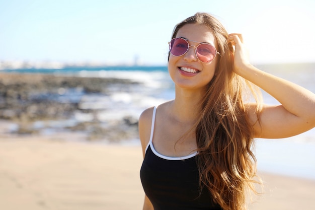 Mujer sonriente con gafas de sol en la playa