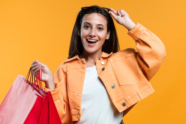 Mujer sonriente con gafas de sol sosteniendo bolsas de la compra.