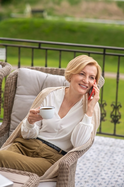 Mujer sonriente hablando por el teléfono celular durante su pausa para el café