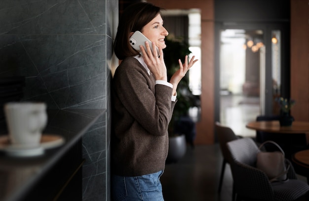 Foto mujer sonriente hablando por teléfono vista lateral