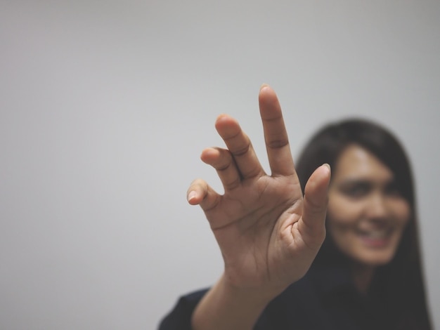 Foto mujer sonriente haciendo gestos contra un fondo gris