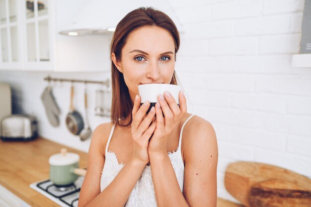 Mujer sonriente hermosa joven que bebe el café de la mañana.