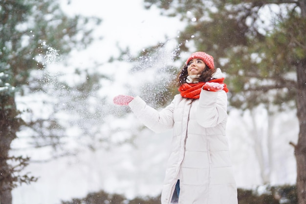 Mujer sonriente de invierno con sombrero rojo posando en un parque nevado Clima frío Vacaciones de moda de invierno