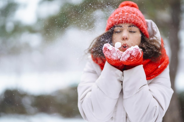 Mujer sonriente de invierno con sombrero rojo posando en un parque nevado Clima frío Vacaciones de moda de invierno