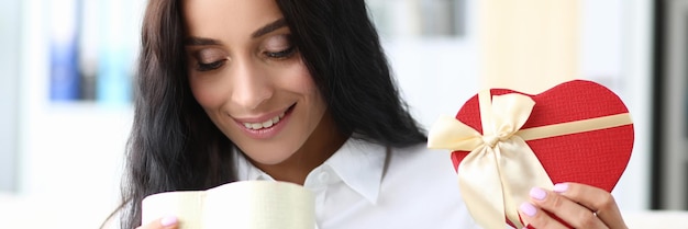 Mujer sonriente joven abre caja de regalo closeup