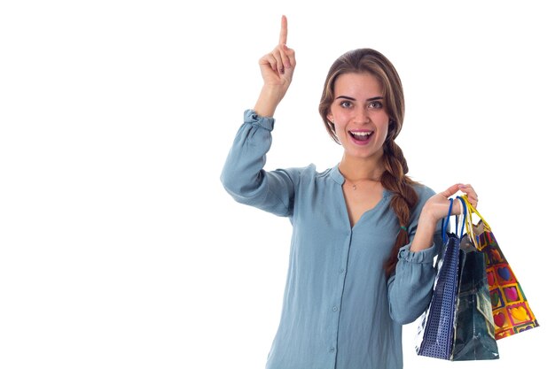 Foto mujer sonriente joven en blusa sosteniendo bolsas de compras multicolores y sosteniendo algo en su mano