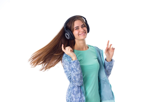 Mujer sonriente joven con cabello castaño en camisa azul en auriculares negros girando sobre fondo blanco en estudio
