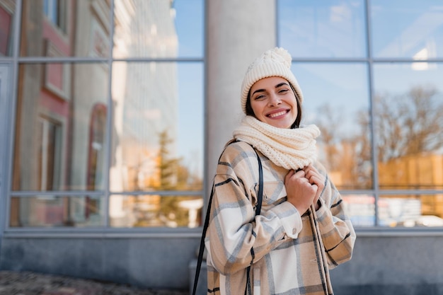 Mujer sonriente joven caminando en la calle en invierno