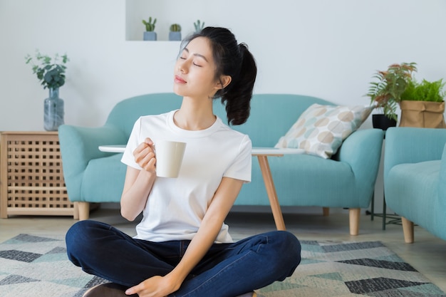 Mujer sonriente joven en camiseta blanca disfruta de una taza de café.